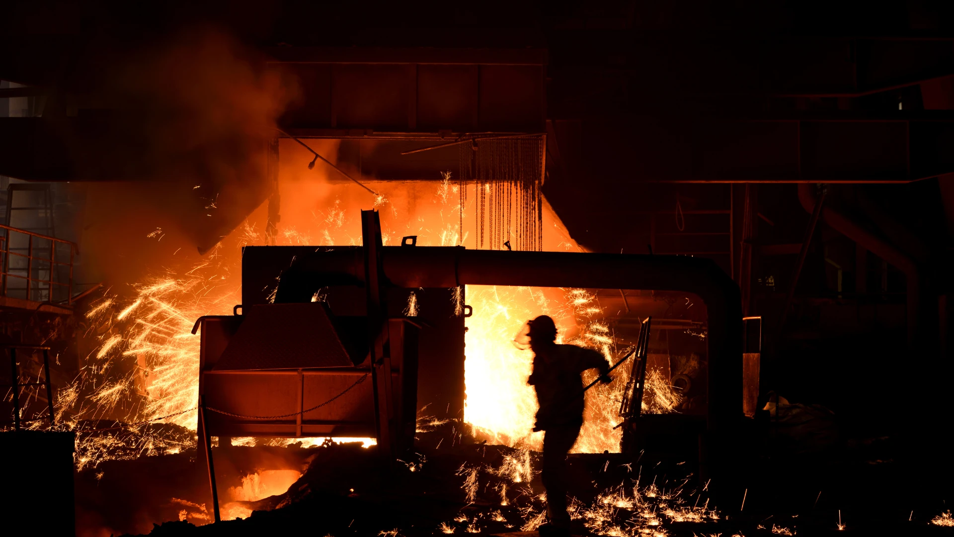 Coke supplier for steelworks – a steelworker at the blast furnace with visible flames and sparks during the steelmaking process.