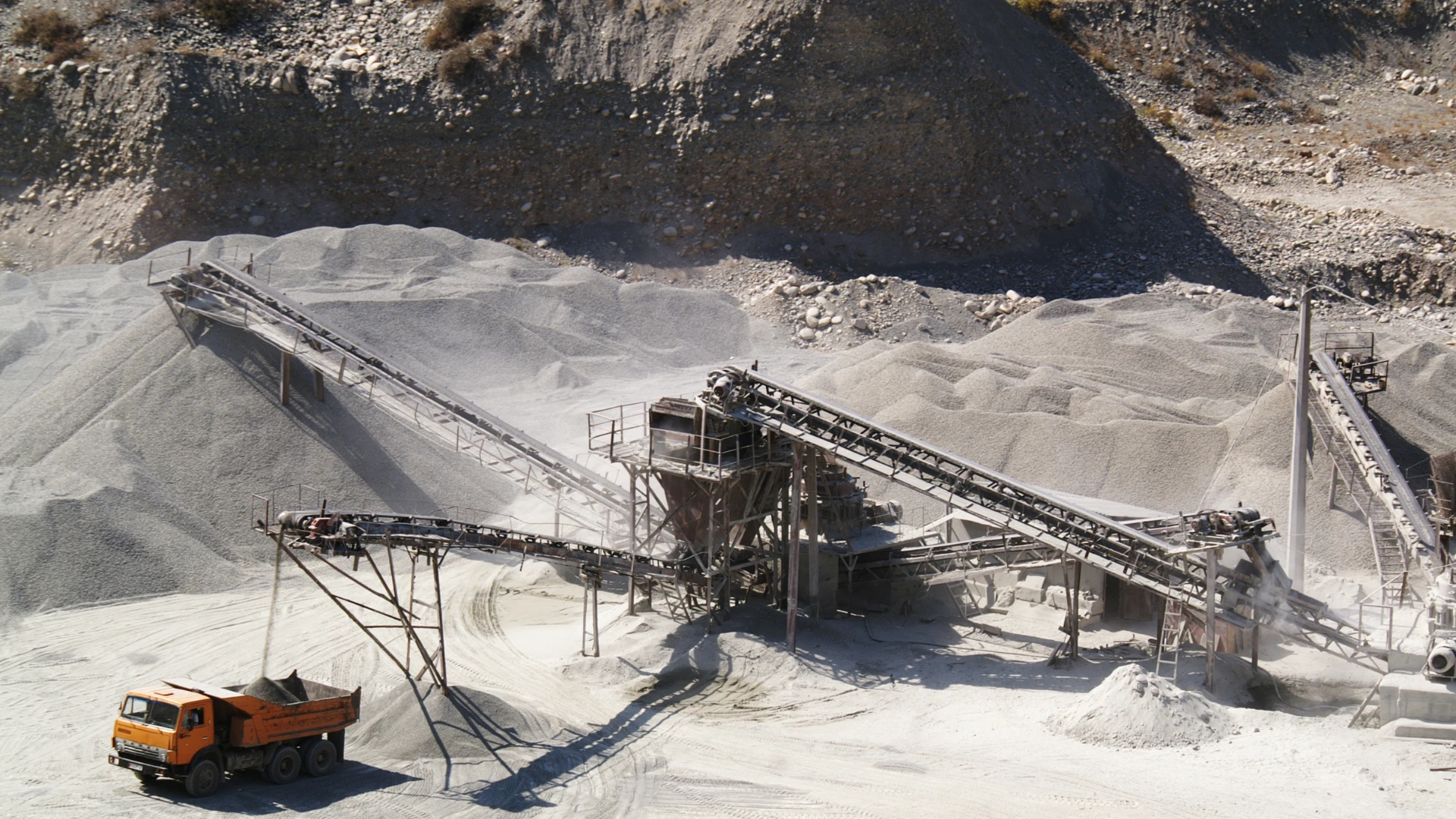 Dostawca surowców mineralnych dla przemysłu – zakład przeróbki kruszyw z taśmociągami i ciężarówką załadowczą w kopalni odkrywkowej.