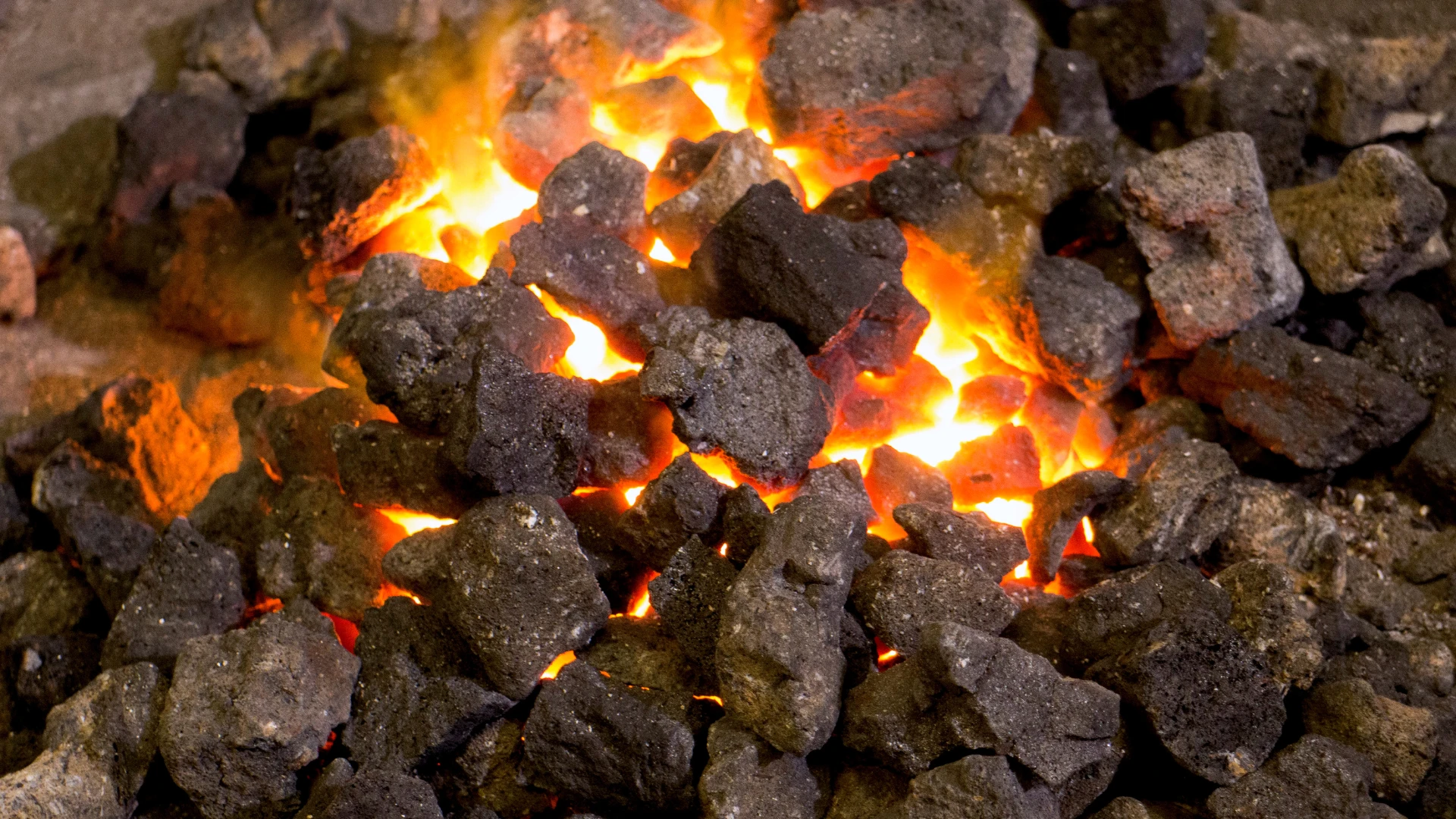 Lieferant von Kokskohle – Glühende Stücke von Kokskohle, die während des Verbrennungsprozesses intensive Wärme und Flammen abgeben.