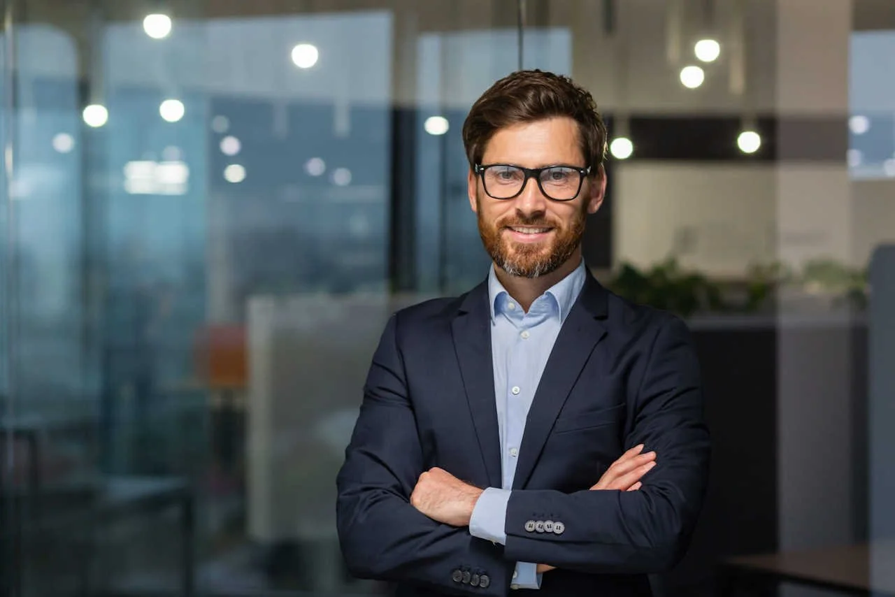 Work in the energy resources industry – a man in a suit and glasses standing in an office, symbolizing professionalism in the energy sector.