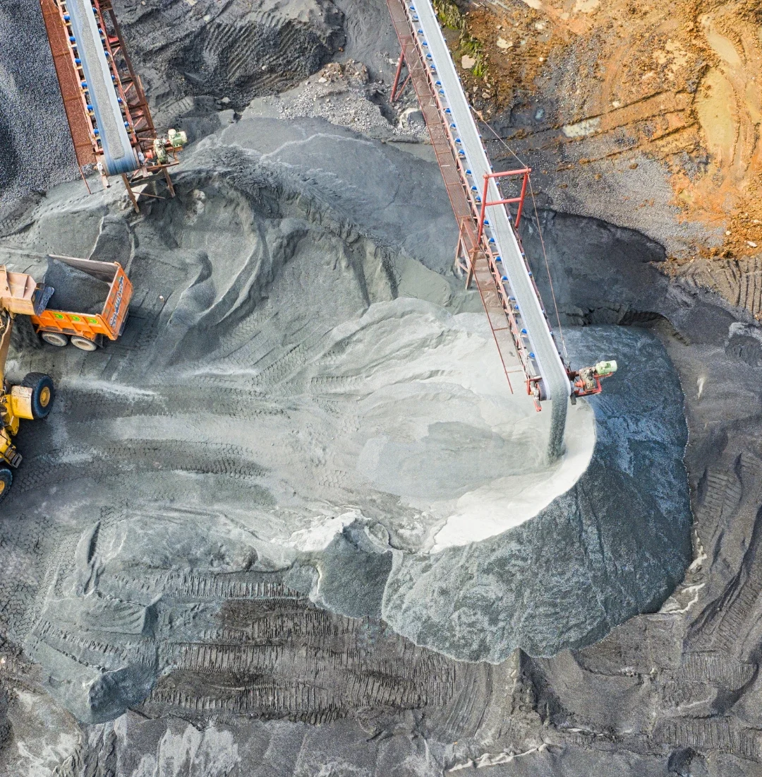 Coal tar supplier – aerial view of an industrial plant with conveyor belts and trucks transporting raw materials.