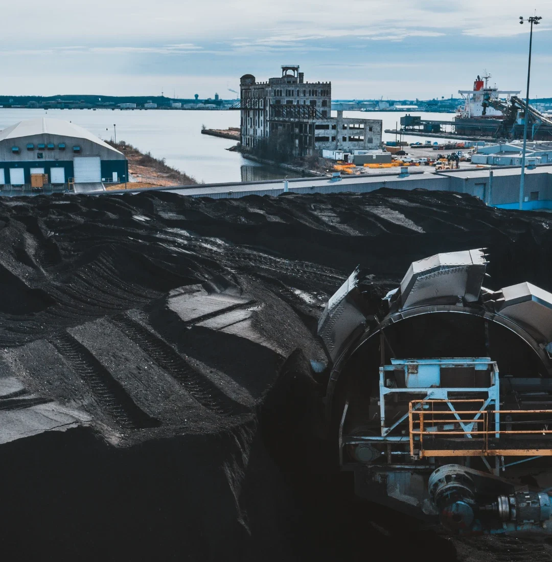 Dostawca smoły węglowej – przemysłowy terminal z hałdami węgla i infrastrukturą portową do transportu surowców energetycznych.