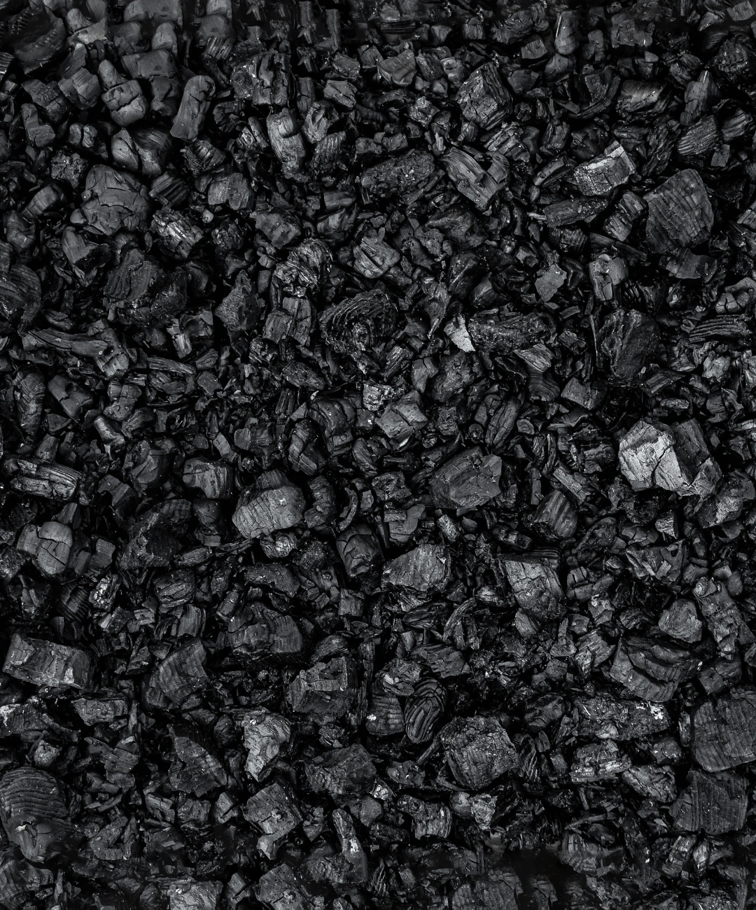 Wholesale coal sales — a close-up of small, shiny lumps of hard coal stacked densely, symbolizing raw material ready for wholesale distribution.